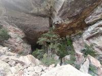 Entrada principal da Gruta, evidenciando o perfil estratigráfico, com arenitos na base e conglomerados no topo. Este contato controla o desplacamamento de blocos e o desenvolvimento da caverna. Dentro do pacote arenítico, ocorre o tufo vulcânico, de coloração cinza. (Foto: Raphael Parra)